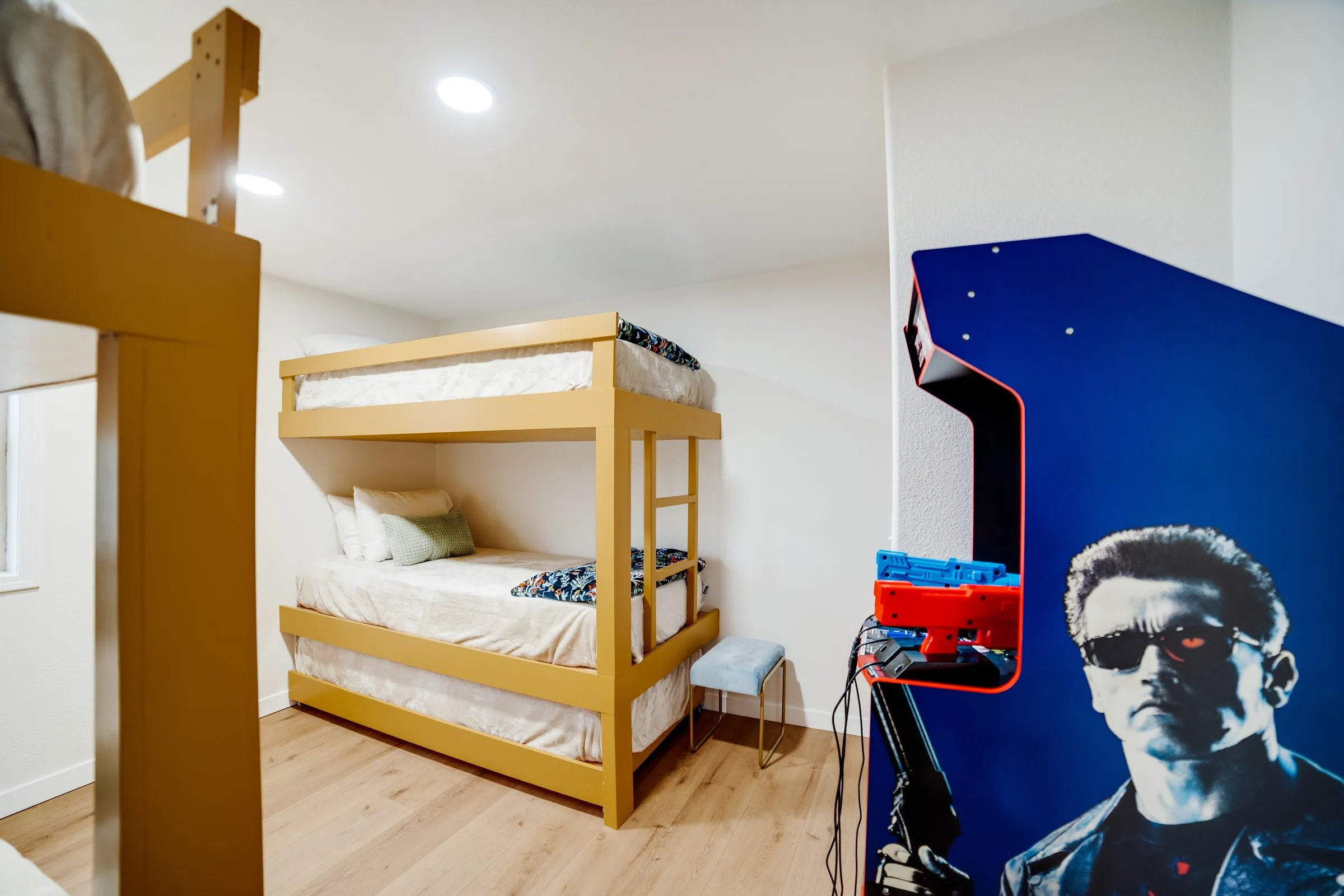 Kids’ bunk room with two sets of bunk beds and a Terminator 2 arcade cabinet